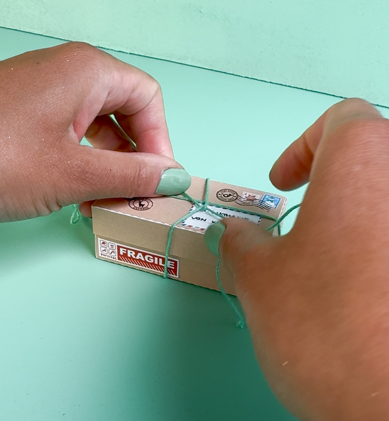 Wichtelgeschenk Fee Reagenzglas: geöffnete Kraftpapier-Paketbox mit Watte Goldsternen und Glasfläschchen mit Fee