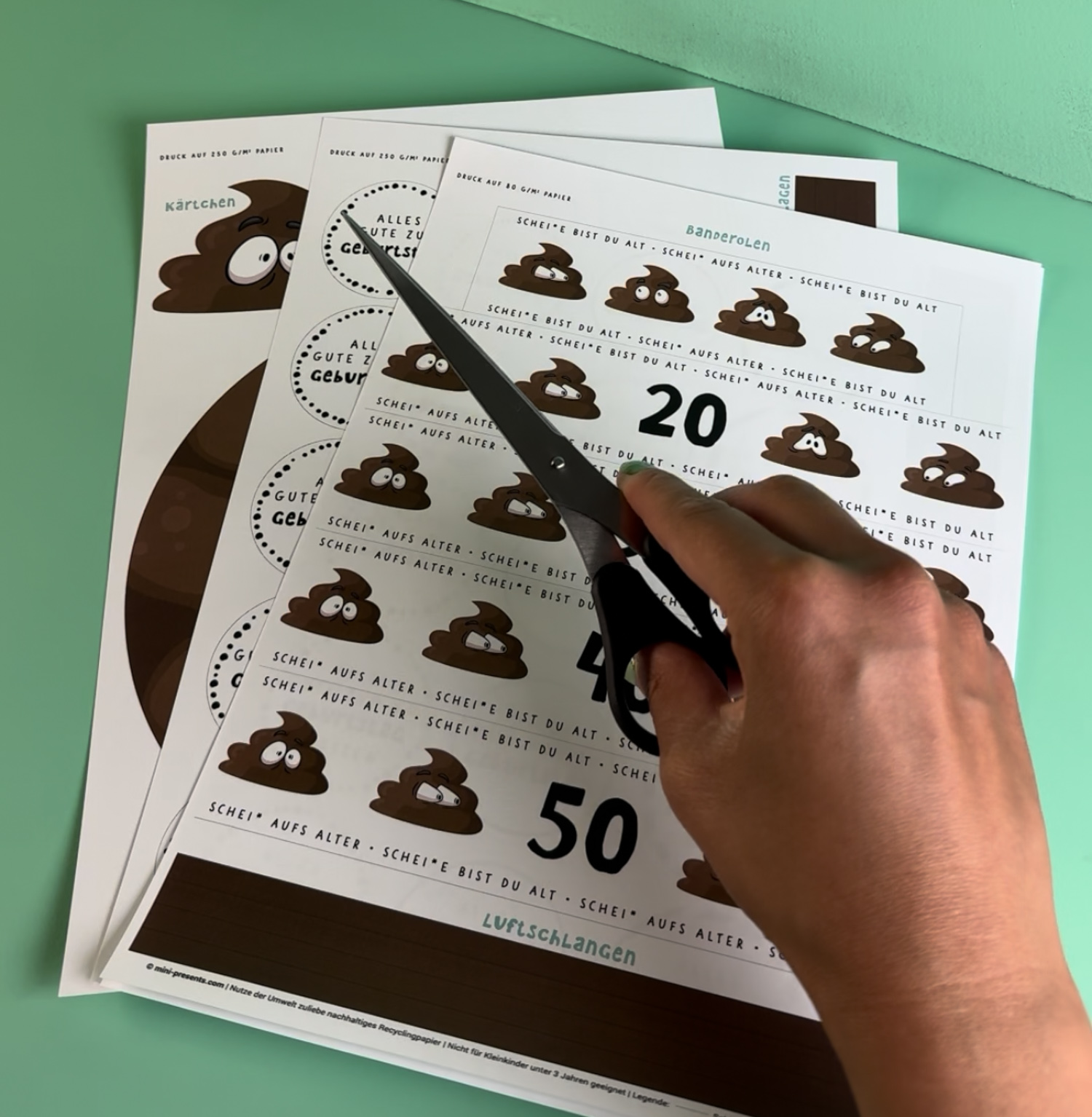Witziges Geldgeschenk zum 50. Geburtstag als Klorolle mit Banderole, Kackhaufen mit Wackelaugen, Geldschein Kerzen und Schild Alles Gute zum 50. Geburtstag, mintgrüner Hintergrund