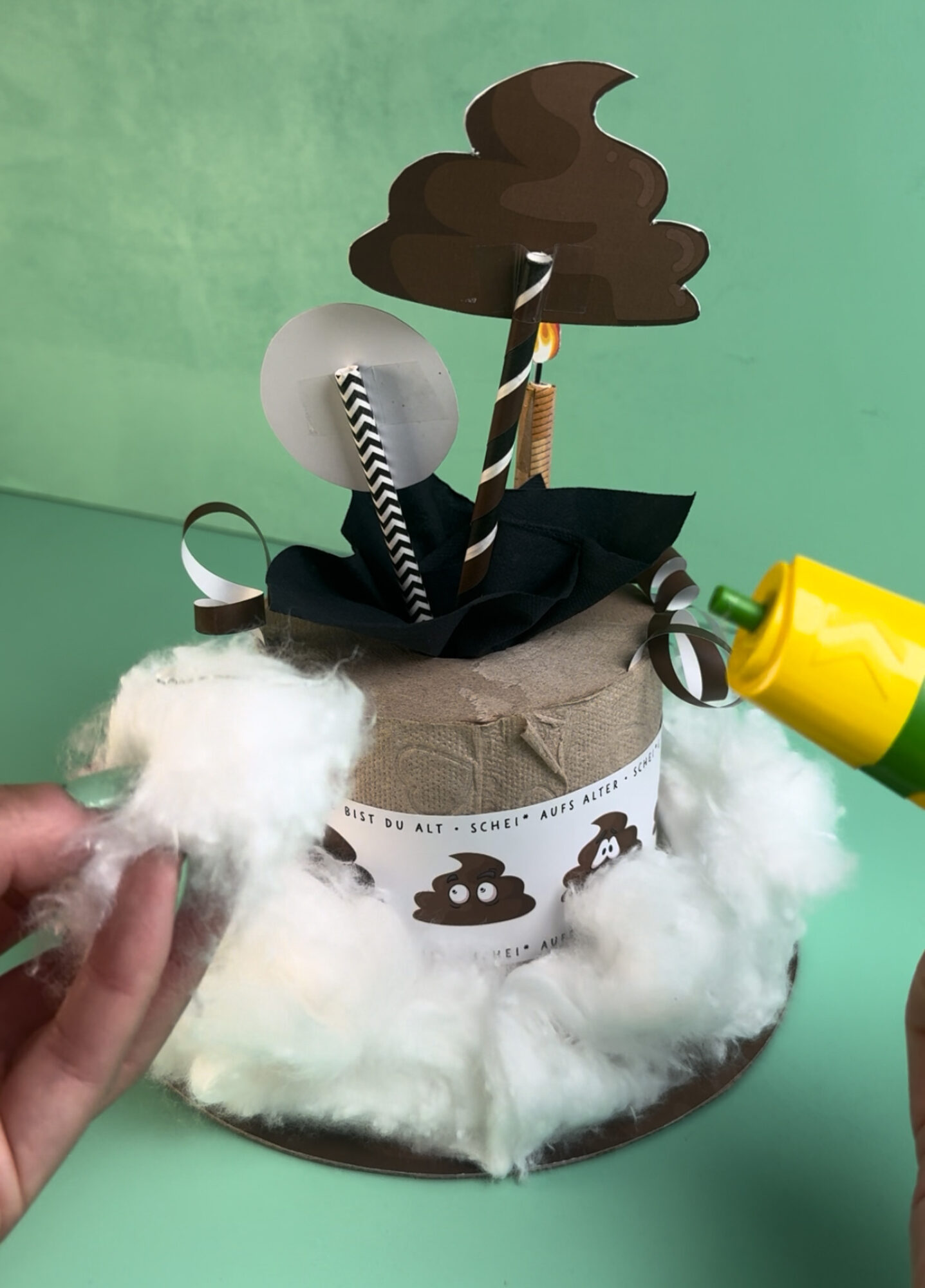 Witziges Geldgeschenk zum 50. Geburtstag als Klorolle mit Banderole, Kackhaufen mit Wackelaugen, Geldschein Kerzen und Schild Alles Gute zum 50. Geburtstag, mintgrüner Hintergrund