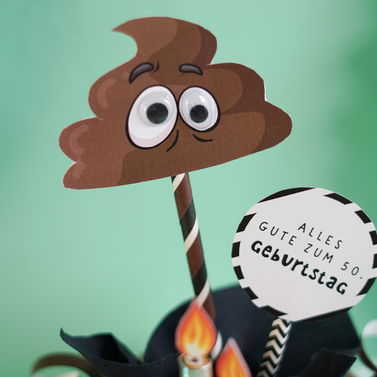Witziges Geldgeschenk zum 50. Geburtstag als Klorolle mit Banderole, Kackhaufen mit Wackelaugen, Geldschein Kerzen und Schild Alles Gute zum 50. Geburtstag, mintgrüner Hintergrund