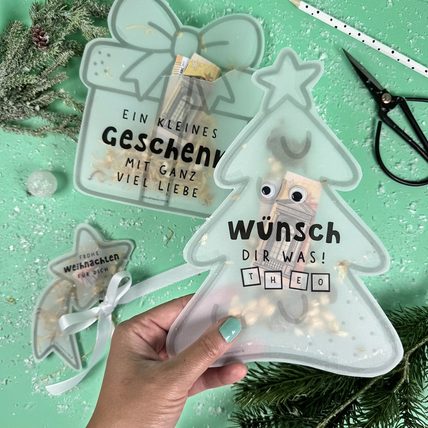 Hand hält die Konfettikarte Tannenbaum mit Wackelaugen und Namen Theo über den anderen Weihnachtskarten
