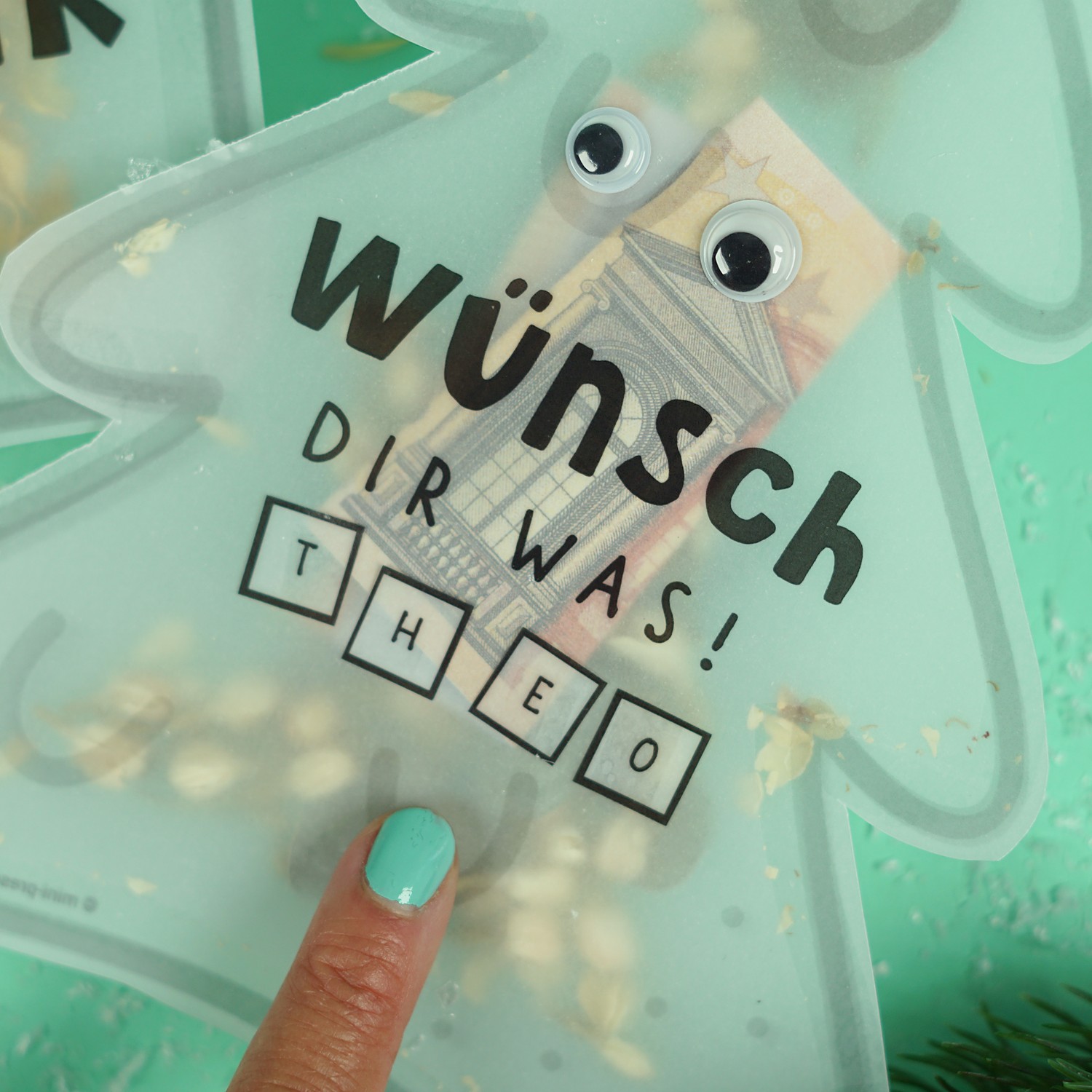 Nahaufnahme der Konfettikarte Tannenbaum mit Wackelaugen, Geldschein und Buchstaben für den Namen