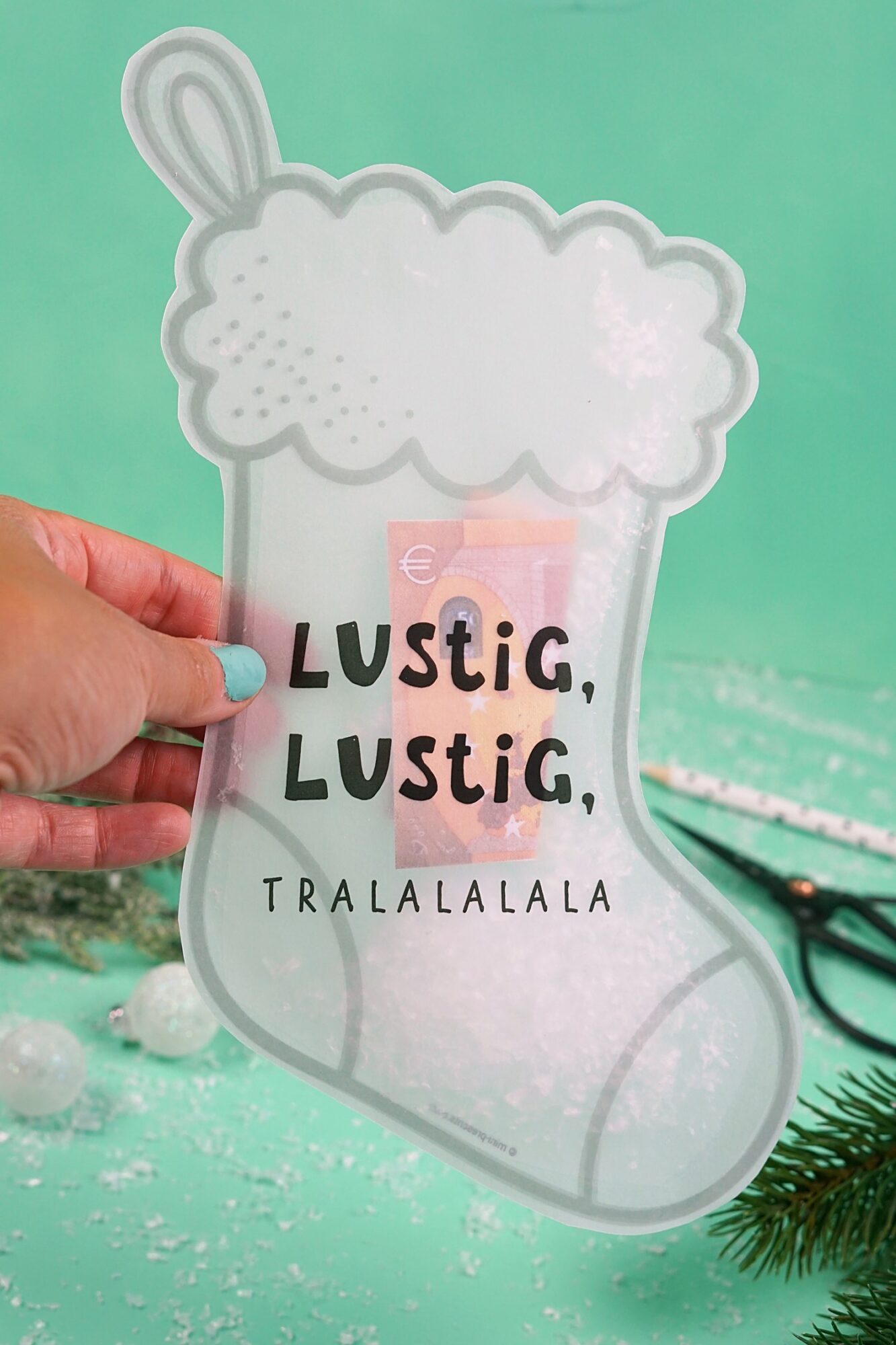 Hand hält die Schüttelkarte Stiefel mit dem Spruch Lustig, lustig, tralalalala